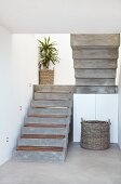 Concrete staircase with wooden treads and potted palm on landing