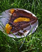 Ein Stück Schokoladen-Orangen-Tarte auf Teller im Gras