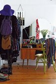Retro dressing table, bright green wicker chair and open clothes rack in bedroom