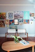 Webbed armchairs and kidney-shaped table with colourful gallery of various pictures on wall in background