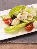 Caesar salad with mozzarella, olives and tomatoes