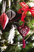 Besticktes Weihnachtsherz mit NOEL-Schriftzug an rotweiss geschmücktem Weihnachtsbaum