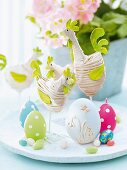 Easter decoration - fabric hens, egg-shaped candles and chocolate eggs on white platter