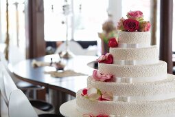 Elegante Hochzeitstorte mit weissen Schleifen und pinkfarbenen Rosen