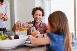 Familie trinkt Orangensaft zum Frühstück