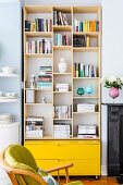 Shelving in niche above bright yellow drawers as modern element between rounded kitchen shelving and antique fireplace surround