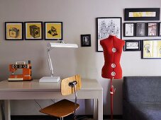 Interior with gallery of pictures, tailor's dummy & table with sewing machine and table lamp