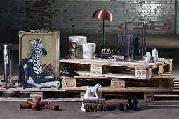 Bizarre objects and decorative items on stacked euro pallets against old brick wall