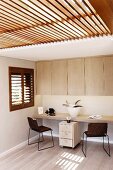 Simple fitted furniture in home office with slatted glass ceiling