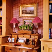 Romantic niche with red houndstooth wallpaper and table lamps on antique bureau