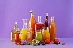 Freshly squeezed fruit juices in assorted glass containers against a purple background