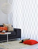 White, wave-shaped curtain in living room with spherical pendant lamp and grey sofa