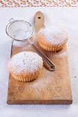 Vanilla muffins with icing sugar on a wooden board