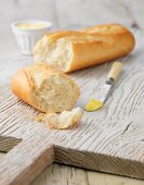 White baguette with butter on white wooden board