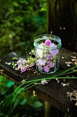 Schnittlauchblüten in einem Schraubglas auf einer Holzbank