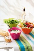 Crudités, salad and pieces of baguette on a garden table