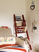 White fitted cupboards and a wooden ladder holding books, next to a sofa