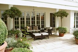 A grand villa - brown outdoor furniture on the stone floor of a terrace with columns and wall of windows