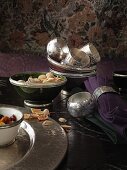 Silver serviette rings, serviettes and bowls with pistachios on a dark table