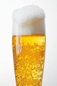 A glass of light beer with overflowing beer foam