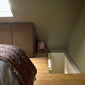 Schlafzimmer im Dachgeschoss mit Treppenaufgang, Bett und Dachfenster, grünen Wänden und Holzboden