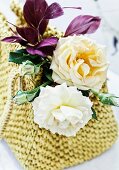 Arrangement of feathers and roses of the varieties 'Lady Hillington' and 'Eifelzauber' in raffia bag