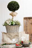 Cushion hand-crafted from hessian and painted with white paint in front of box lollipop tree in wicker planter