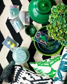 Arrangement of various ceramic pots, green ornaments and photos on black and white rug