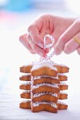 Woman tiding a pile of gingerbread stars garnished with icing