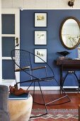 Black, vintage metal rocking chair against blue-painted wall in traditional living room