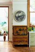 Oriental painted cabinet next to open garden door with view of child in courtyard