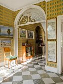 Eingangshalle in englischem Landhaus mit diagonal verlegten Marmorfliesen und Bildergalerie an Wänden mit gemusterter Tapete