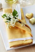 A napkin as a cutlery pocket decorated with elderflowers