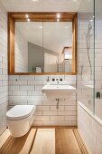 Weiß gefliestes Badezimmer mit rechteckigem Spiegel in Wandnische und einer gläsernen Duschabtrennung