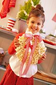 A small girl holding a Christmas wreath made from popcorn