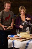 A couple eating a rustic South Tyrolean light meal with dry-cured ham, Schüttelbrot (crispy unleavened bread from South Tyrol), nuts, cheese and wine