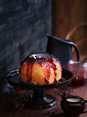 A steamed pudding made in a pressure cooker with strawberry sauce