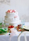 A pistachio and rose meringue cake with strawberry cream decorated with candid rose petals