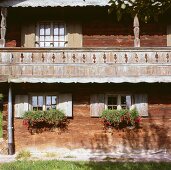 Wettergegerbte Balkonfassade mit natürlicher Patina und Blumenkästen mit Hängegeranien