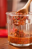 Fiery sauce in a glass with a wooden spoon