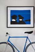 Contemporary blue and black artwork and racing bike in matching colours against white wall