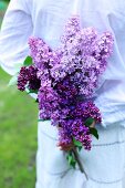 A woman holding purple lilac flowers