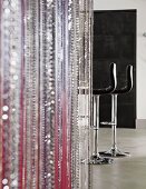 Bead curtain in various colours; black leather bar stools in background