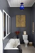 Black-painted and partially tiled bathroom with bathtub, toilet & framed mirror