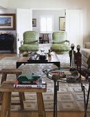 Rustic wooden stools & metal side table in living room with armchair in front of open double doors