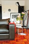 Partially visible leather couch and retro lamp on side table on mosaic parquet floor