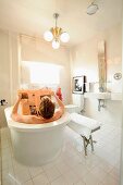 Man bathing in free-standing bathtub in modern, white bathroom