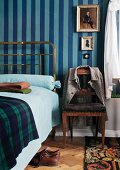 Stilechtes Messingbett mit Biedermeierstuhl vor englischen Wandstreifen in Blautönen