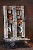 Decorative plates on open shelving made from wooden pallet on furniture dolly against corten steel wall