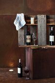 Wine bottles and glasses in wall cabinet made from sections of pallet on corten steel cube